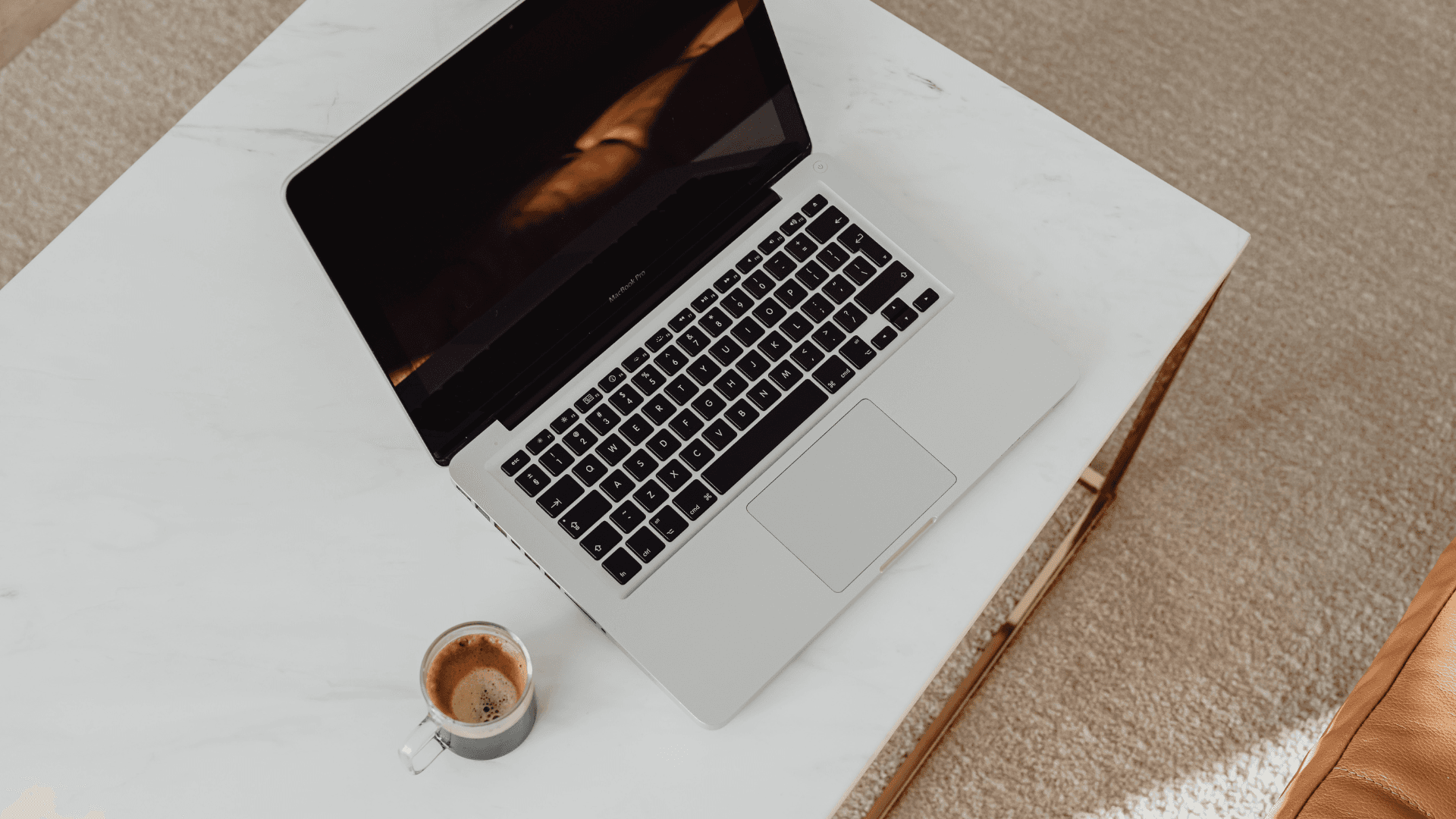 Portátil y café sobre mesa de mármol, entorno de trabajo digital moderno